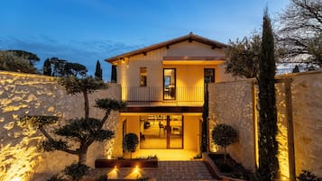 A two-story house with a balcony, stone walls, and a well-lit entrance.