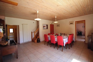 A dining area with a wooden ceiling, a staircase, and a dining table set for four.