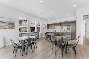 A modern kitchen with stainless steel appliances, a dining area with glass-top tables and metal chairs, and a large painting on the wall. - Blissful Poolhouse #62: Private Pool (Santa Clara)