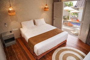 A bedroom with a bed, bedside tables, and a view of an outdoor balcony. - Hu'u Beach Front Hotel (Nusa Tenggara Barat)