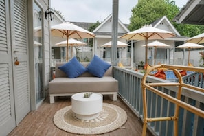 Un balcon avec un canapé, une petite table ronde et des parasols.