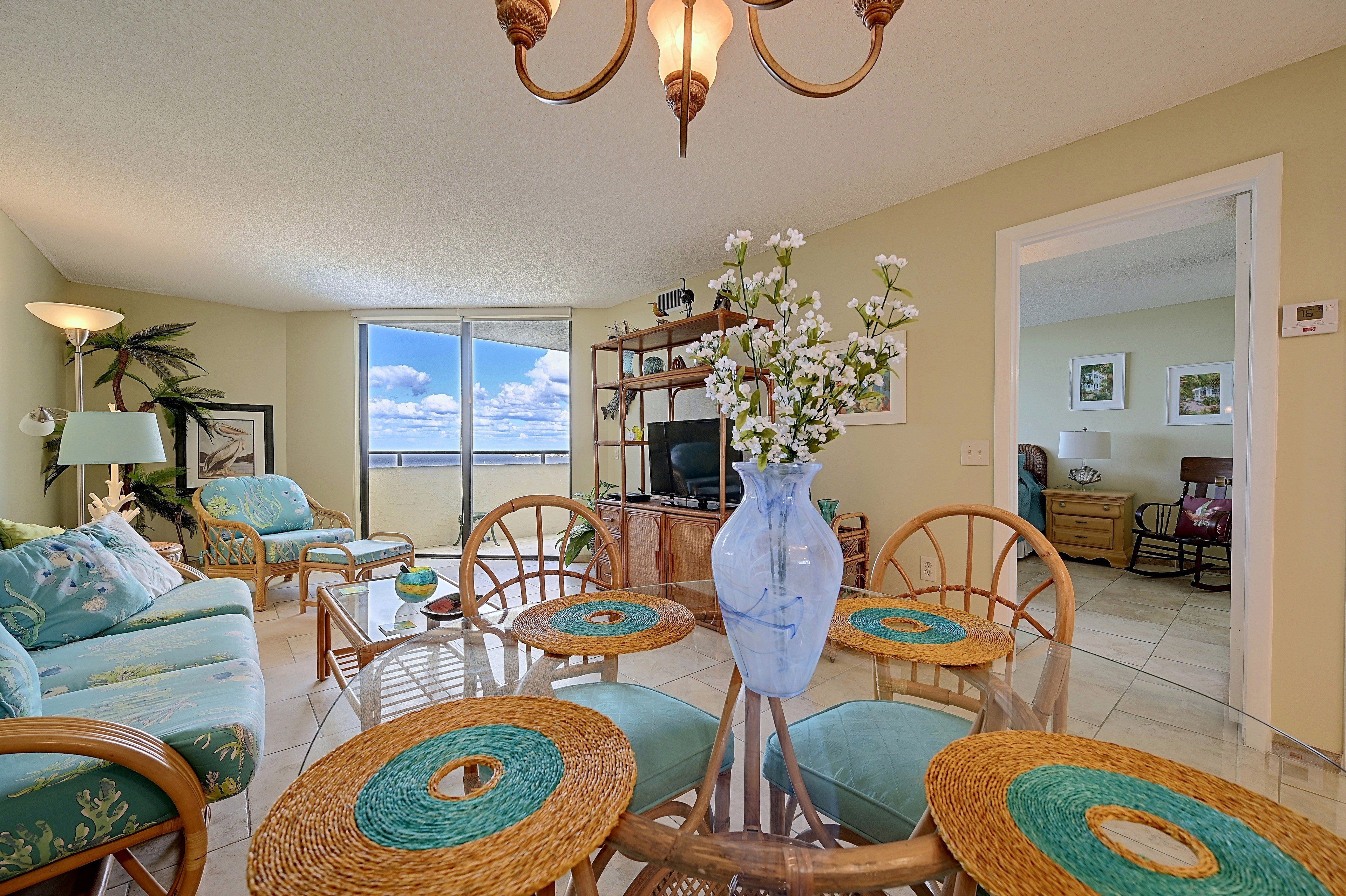 A living room with a sofa, chairs, a coffee table, a TV, and a vase with flowers.