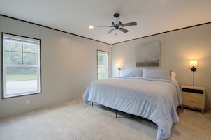 Un dormitorio con cama, ventilador de techo, mesita de noche y ventana.