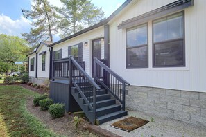 A two-story building with a staircase leading to the entrance, a front door, and large windows.