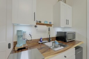 Una kitchenette equipada con microondas, cafetera y un estante pequeño con frascos.