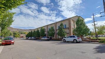 A parking lot with several cars, a building with a brick facade, and trees.