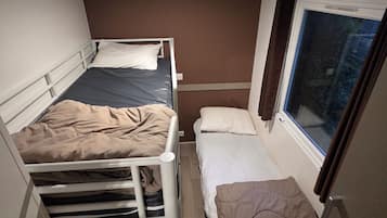 Une petite pièce, de taille modeste, avec deux lits superposés et une fenêtre donnant sur l’extérieur.