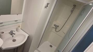 Une salle de bain moderne avec une douche à parois de verre, un lavabo avec un miroir et des toilettes.