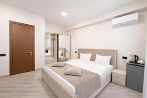 Un dormitorio con cama, mesitas de noche, armario, espejo y aire acondicionado.