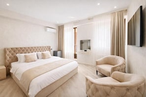 Una habitación de hotel con una cama grande, televisión, una silla y un escritorio.
