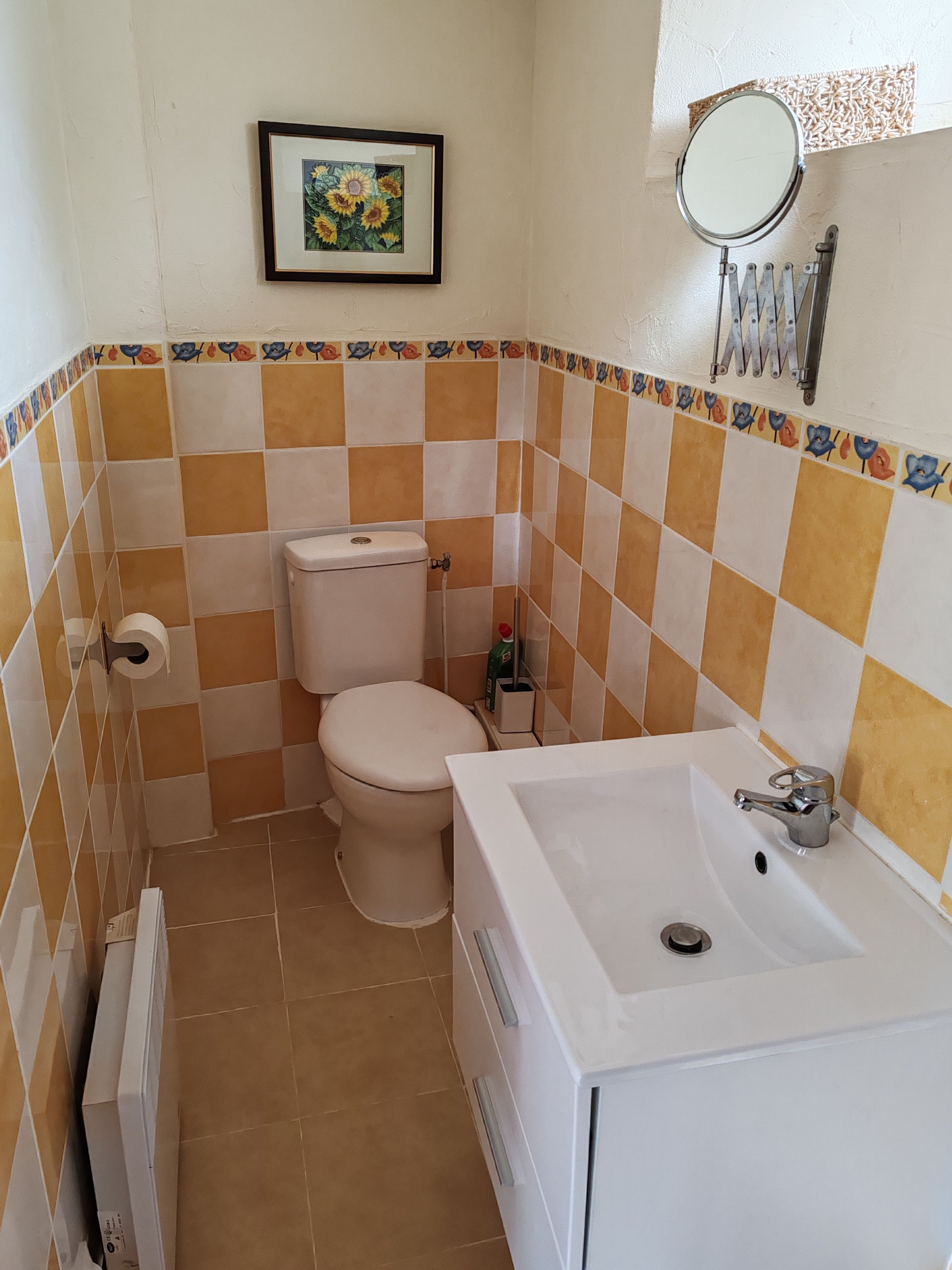Un baño con inodoro, lavamanos y un cuadro en la pared.