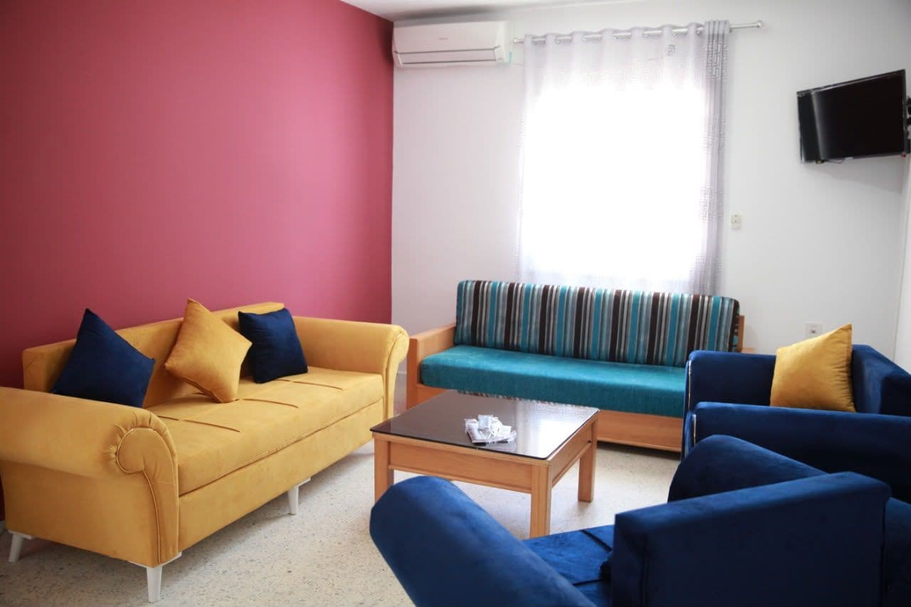 Una sala de estar con un sofá amarillo, un sofá azul, un sofá a rayas y una mesita de centro.