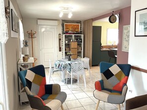 Un comedor con una mesa y sillas, una cocina al fondo y un reloj en la pared.