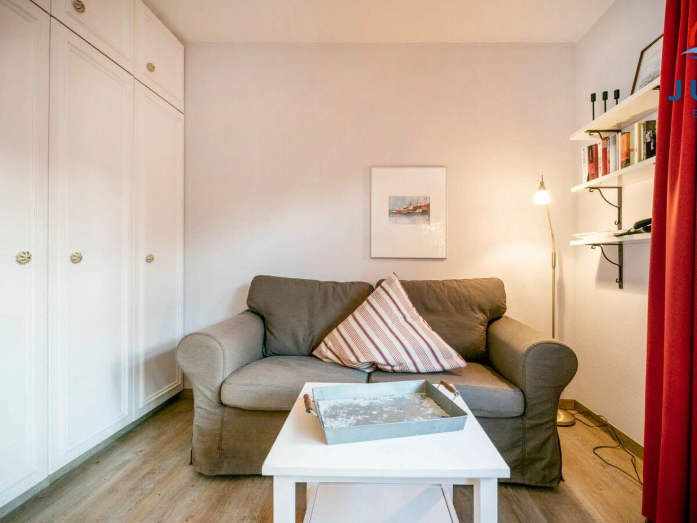 A living room with a sofa, a small table, a lamp, and a bookshelf.