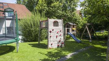 A playground with a climbing structure, a slide, and a swing set.