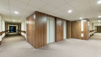 A corridor with wooden doors and a carpeted floor.
