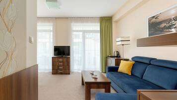 A modern living room with a blue sofa, wooden coffee table, and a TV on a wooden cabinet.