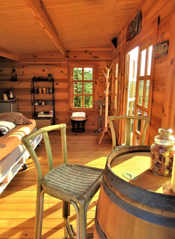 A cozy cabin interior with a wooden interior, a bunk bed, a dining table, and a large window. - Cottage '"Intimité" Avec Ou Sans Spa -' with Private Garden and Wi-Fi (Léguillac-de-l'Auche)