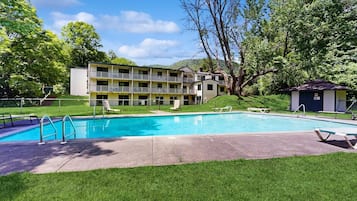 Un hotel con piscina, zona de estar exterior y un edificio con varios balcones.