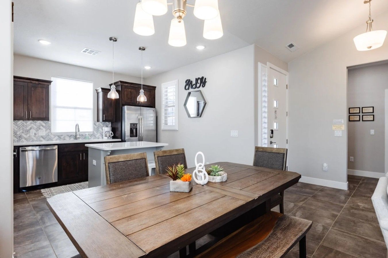 A modern kitchen with dark wood cabinets, stainless steel appliances, and pendant lighting.