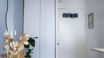 Een hal met een witte deur, een kunstwerk aan de muur en een bloempot op een tafeltje.