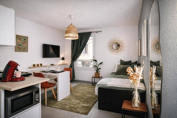 Una camera da letto moderna con un letto, comodini, una scrivania con macchina del caffè, televisione e una finestra con tende.
