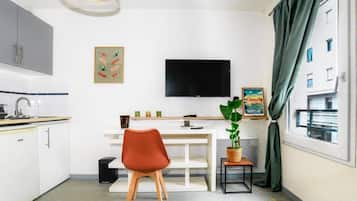 Een compacte keuken met een eethoek, een flatscreen televisie en een potplant.
