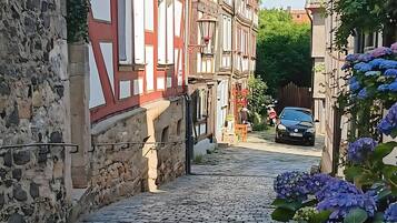 Eine Kopfsteinpflasterstraße, gesäumt von traditionellen Fachwerkhäusern mit Steinmauern, ein Auto ist rechts geparkt.