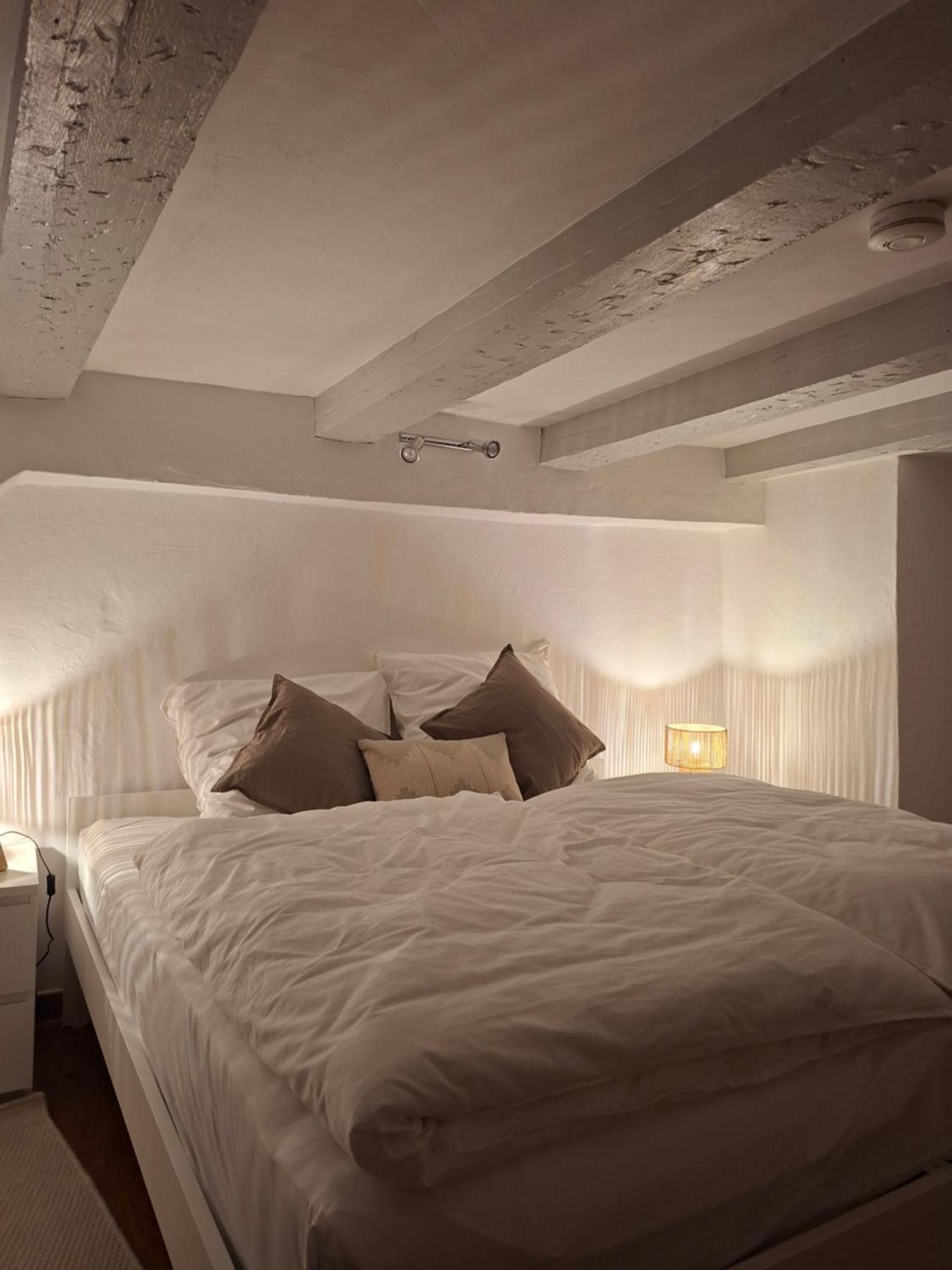 Een slaapkamer met een groot bed, een nachtkastje en een lamp.