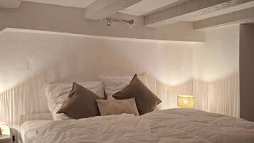 Een slaapkamer met een groot bed, een nachtkastje en een lamp.