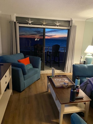 Un salón con sofá, una mesita con bandeja y vista al océano a través de un ventanal.