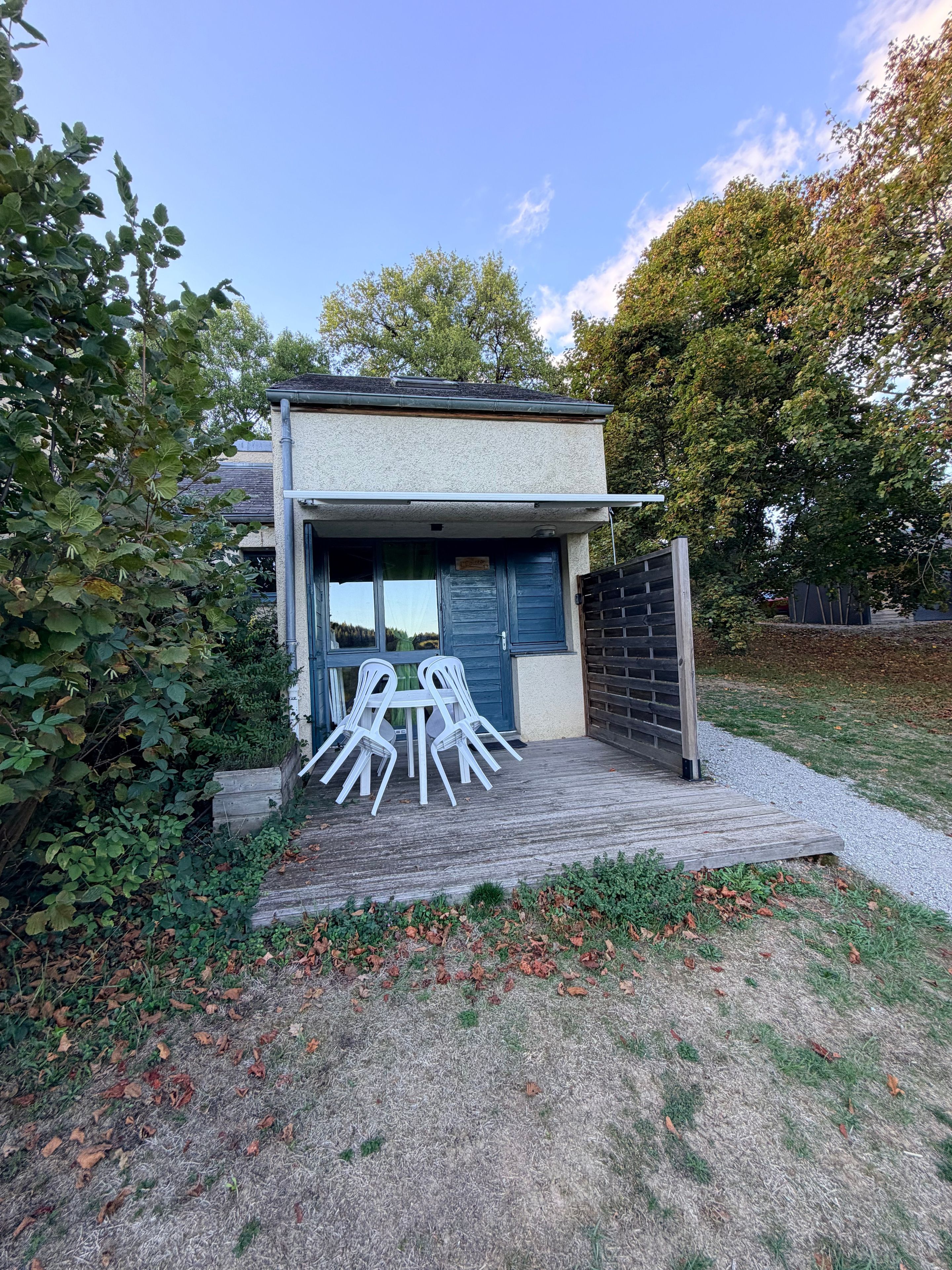 Ein modernes Haus mit einer Garagentür, einer Holzterrasse und Sitzgelegenheiten im Freien.