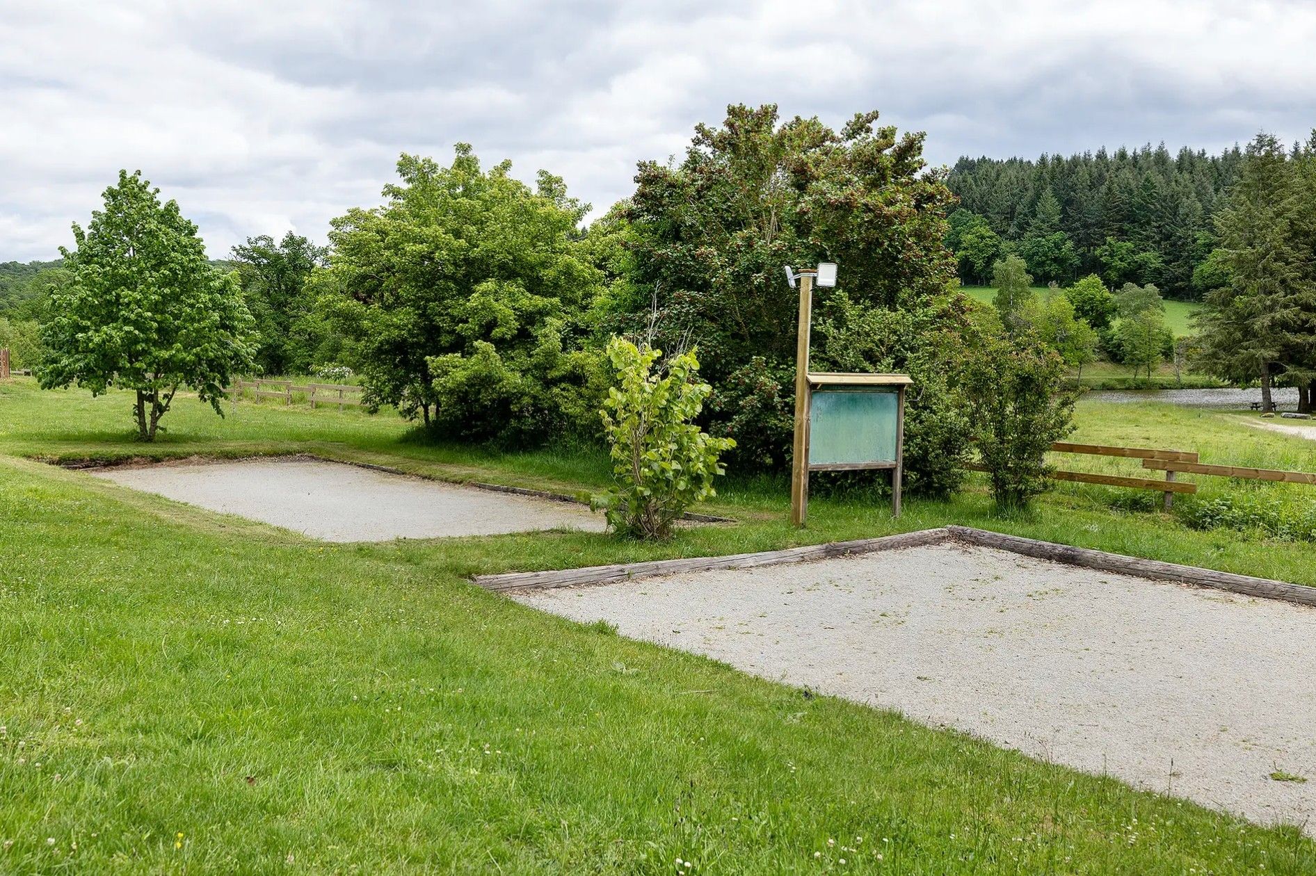 A grassy area with a gravel path, a wooden fence, and a green signpost.