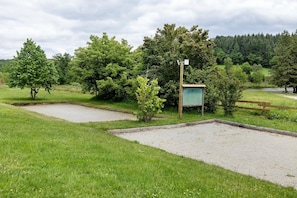 Una zona verda amb un camí de grava, una tanca de fusta i un senyal vertical verd.