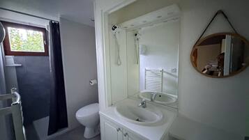 Une salle de bain comprenant des toilettes, un lavabo, une douche et un miroir.