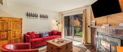 A living room with a red sofa, a wooden coffee table, and a fireplace.