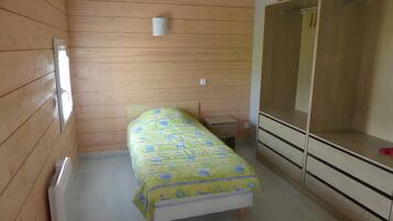 A small, compact room with a bed, a wardrobe, and a radiator.