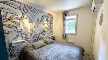 A bedroom with a large bed, a wall mural, a window with curtains, and a radiator.
