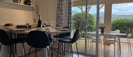 A modern dining area with a table set for four, a view of the outdoors, and a sliding glass door leading to a patio.