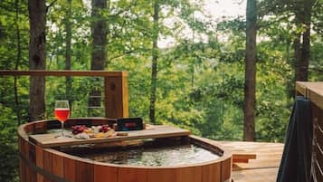 Un jacuzzi de madera con terraza de madera, rodeado de árboles.