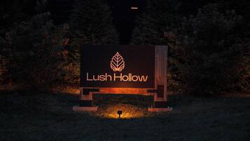 Une enseigne avec le texte « Lush Hollow » et un logo représentant une feuille, le tout sur un fond sombre aux bords illuminés.