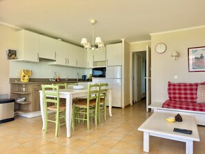 A modern kitchen with white cabinets, a dining table with chairs, a coffee maker, and a microwave.