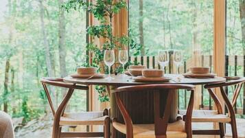 A dining area with a round table, wooden chairs, and a hanging light fixture.