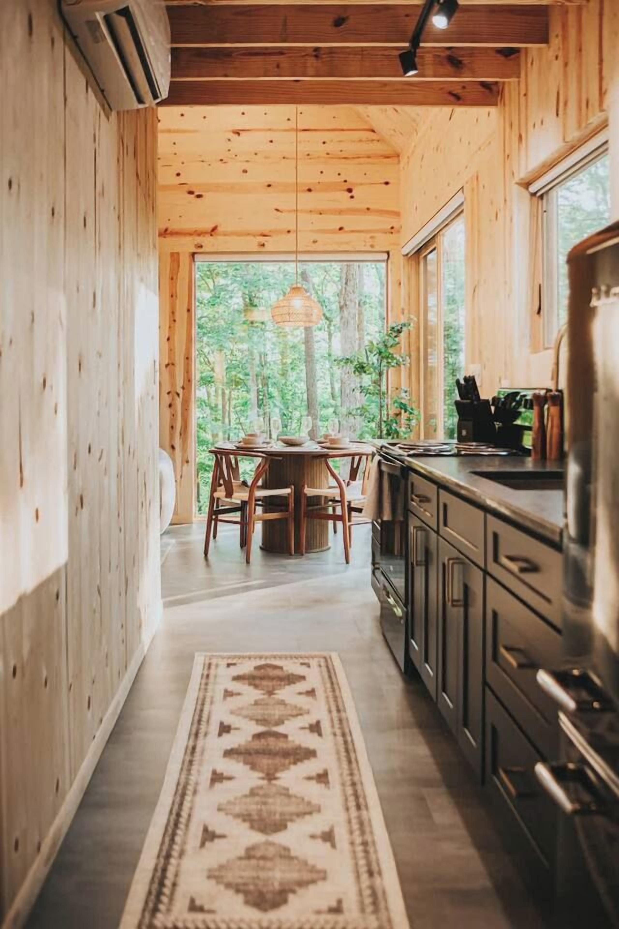 A wooden interior with a dining area, kitchen, and a view of the outdoors.