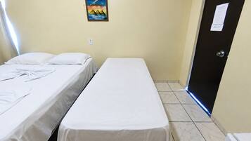 A room with two single beds, a door with a sign, and a painting on the wall.