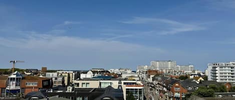 Un horizonte urbano con edificios residenciales y comerciales, cielo despejado y una calle peatonal.