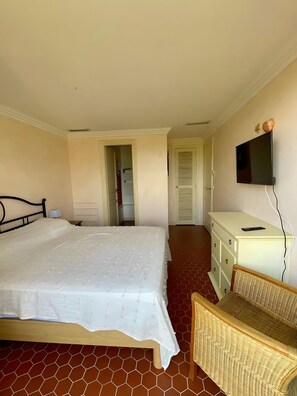 Une chambre à coucher avec un lit, une commode, un téléviseur et une chaise.