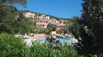 A resort with a swimming pool, lush greenery, and multi-story buildings with balconies.