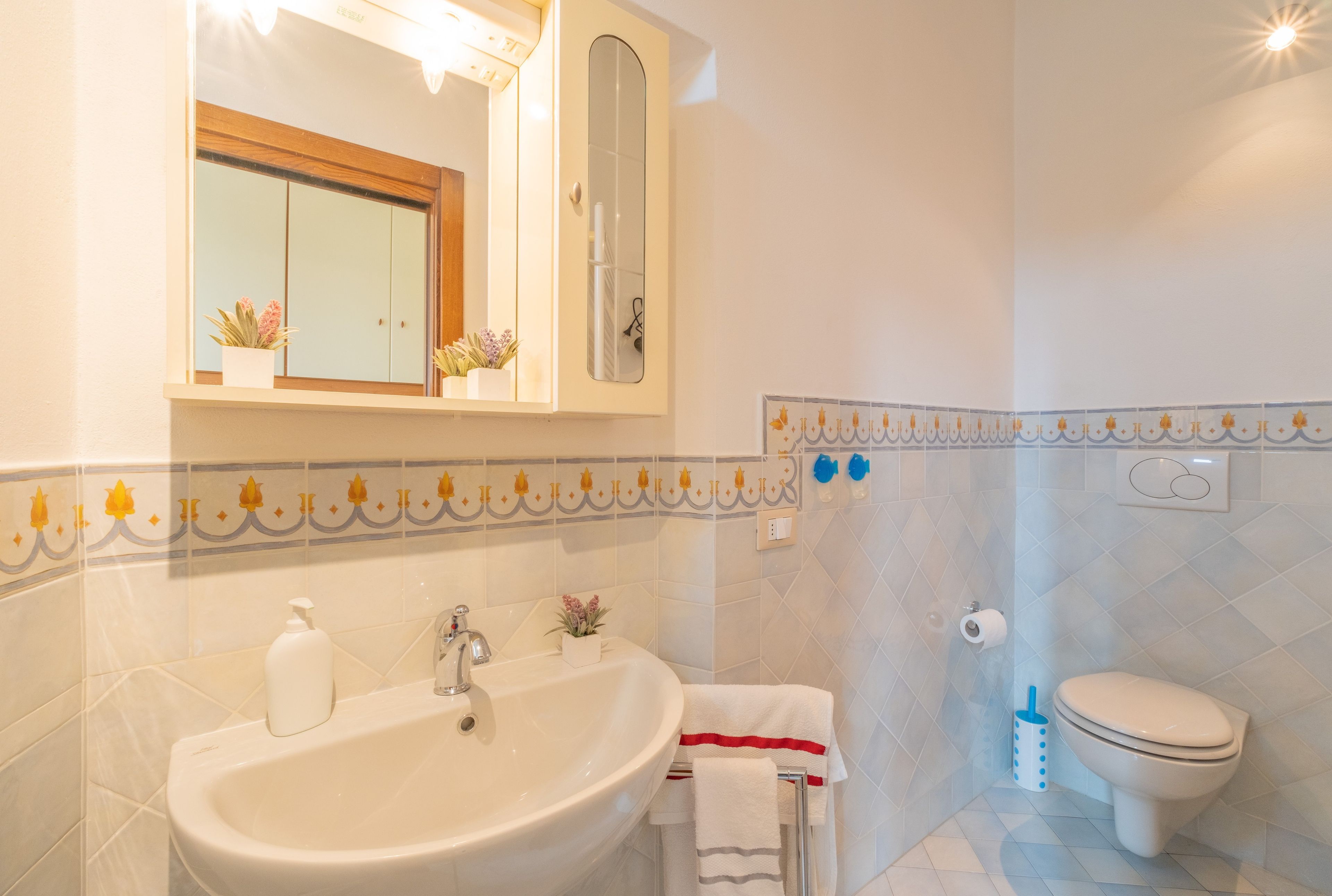 Un bagno con lavandino, specchio, water e piastrelle decorative.