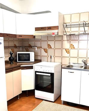 A compact kitchen with white cabinets, a microwave, an oven, and a sink. - Apartment 'Pratolin' with Shared Terrace (Predazzo)